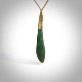 This photo shows a beautiful large jade drop. It is handcarved from a piece of green New Zealand pounamu, with fascinating light green inclusions throughout the stone. We have this on a creme coloured, adjustable four plait cord. We ship this worldwide with an express courier service. Postage is free.